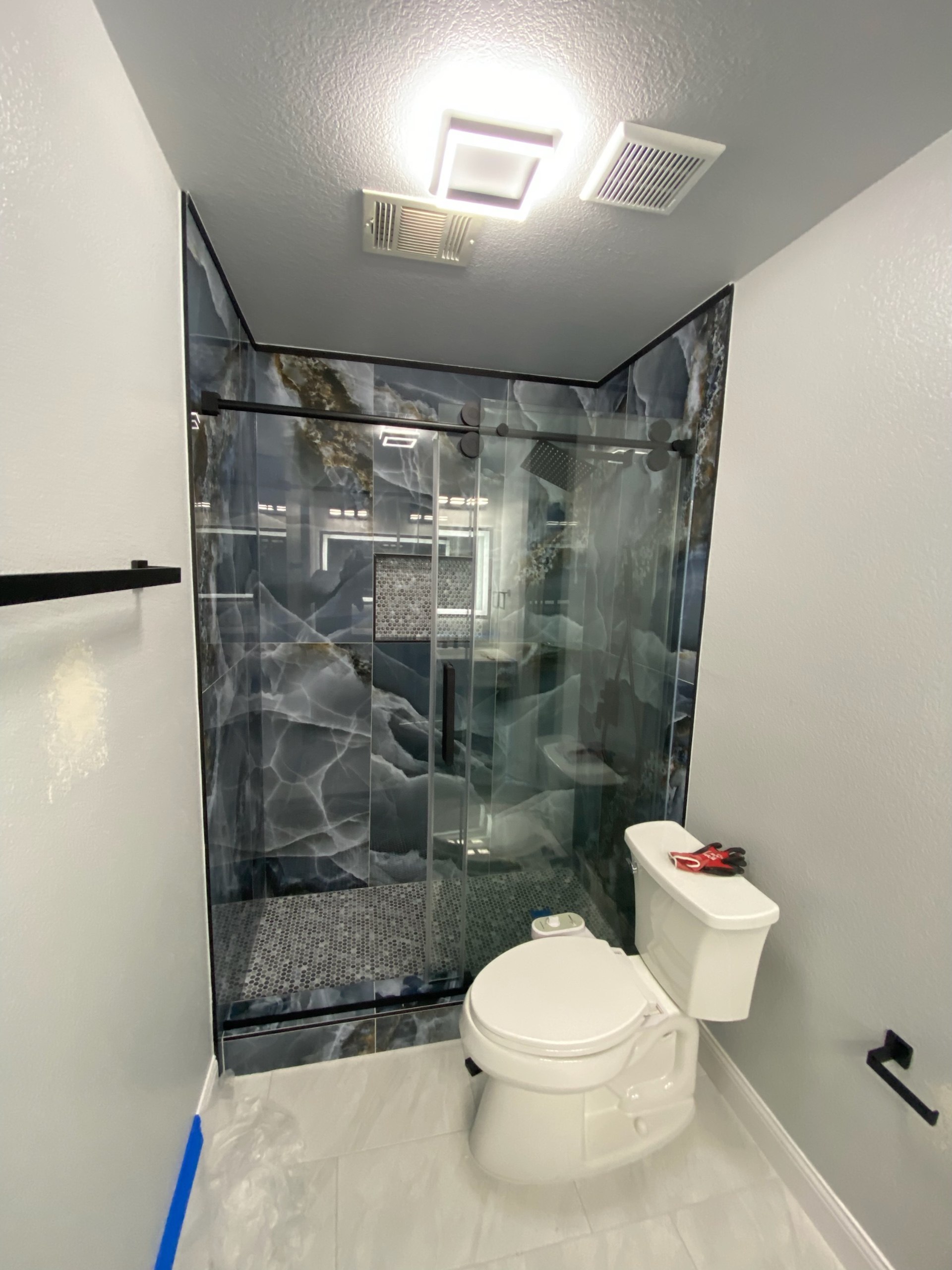 Blue onyx marble shower renovation with black-framed glass sliding door